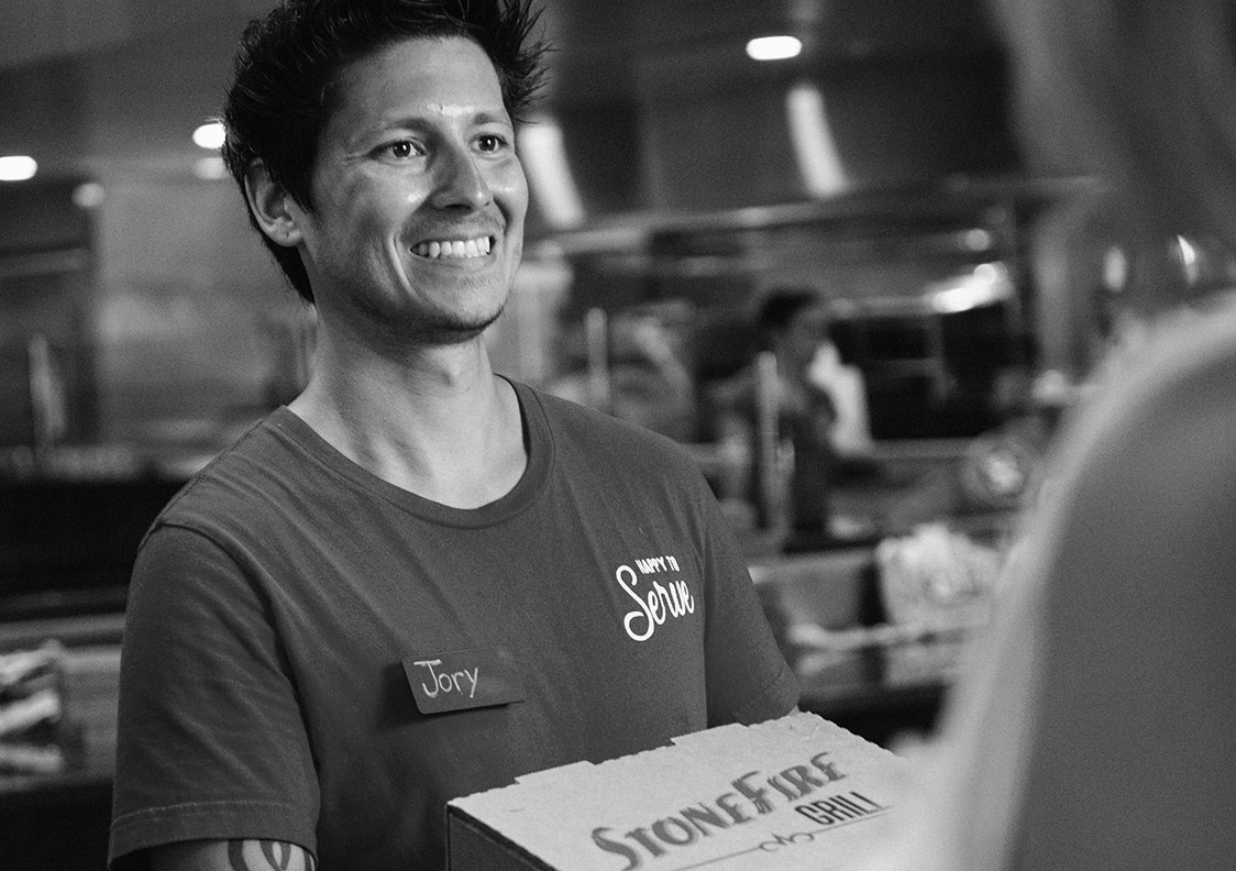 Smiling team member giving take-out food to guest